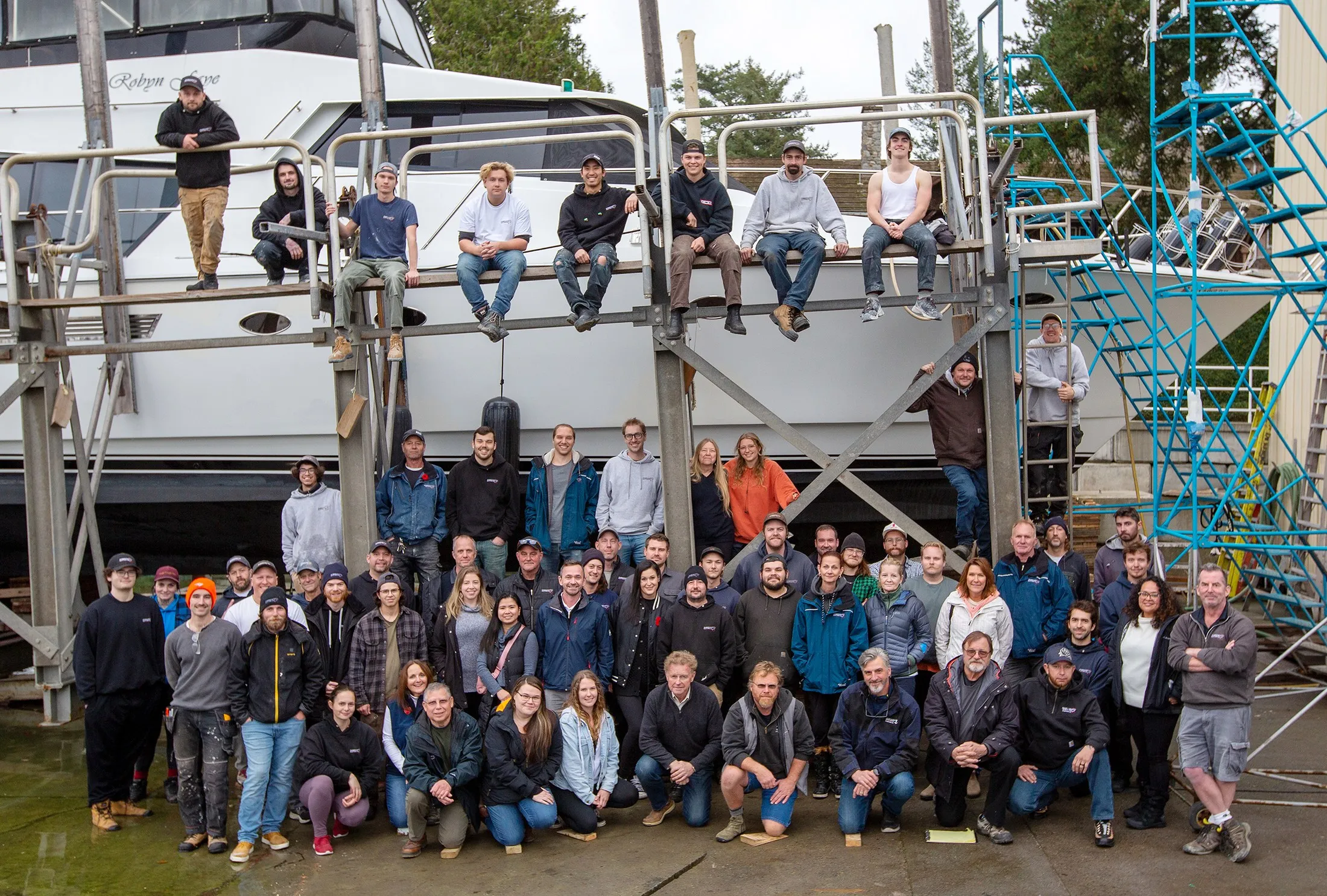The Philbrook's Boatyard crew, gathered on the staging beneath a hauled motor yacht